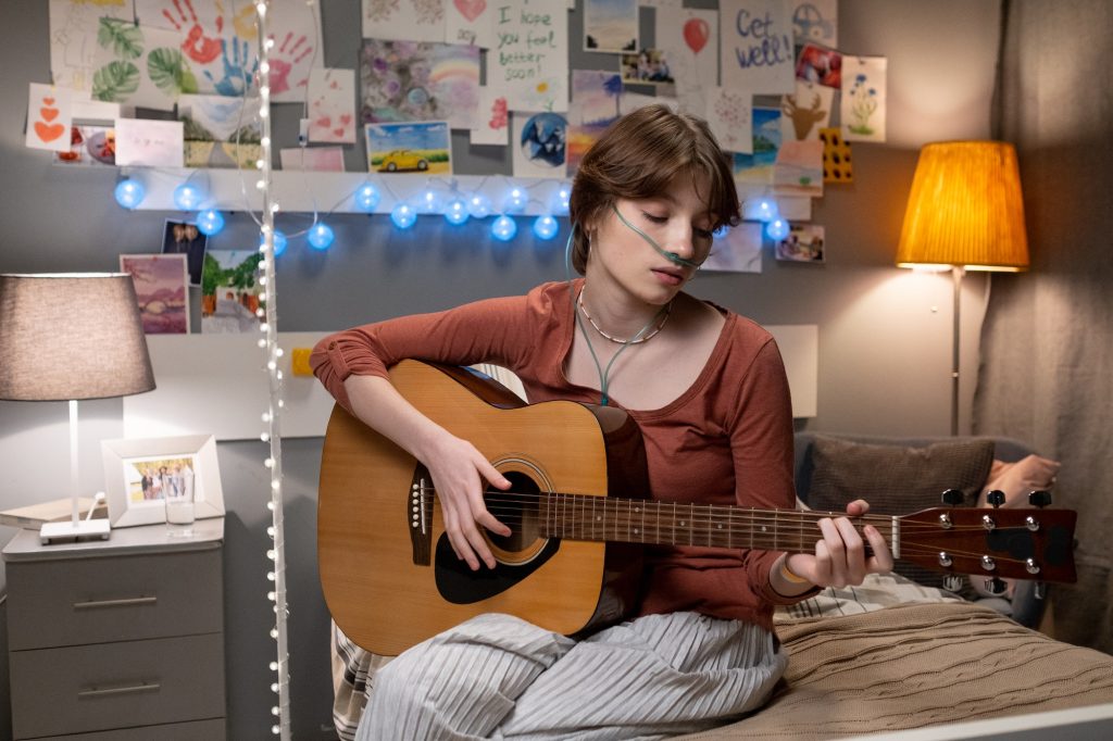 Contemporary teenager playing guitar during online course of music education