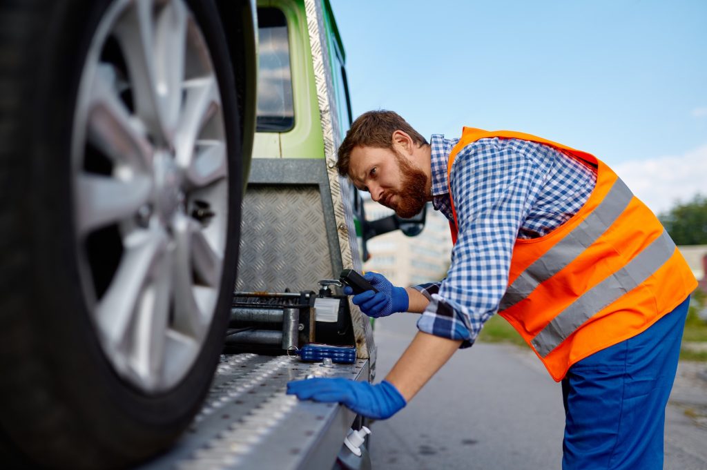 Tow truck operator fixing the car on platform